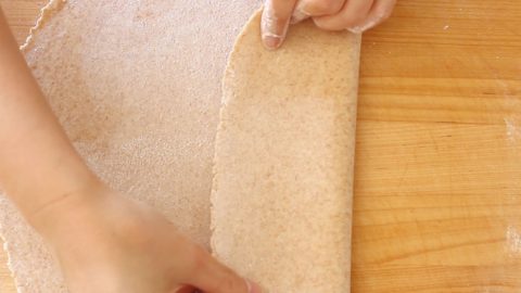 Top-down view of folding rolled whole wheat udon dough.
