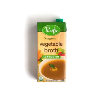 A carton of Pacific brand low-sodium vegetable broth over a white background.