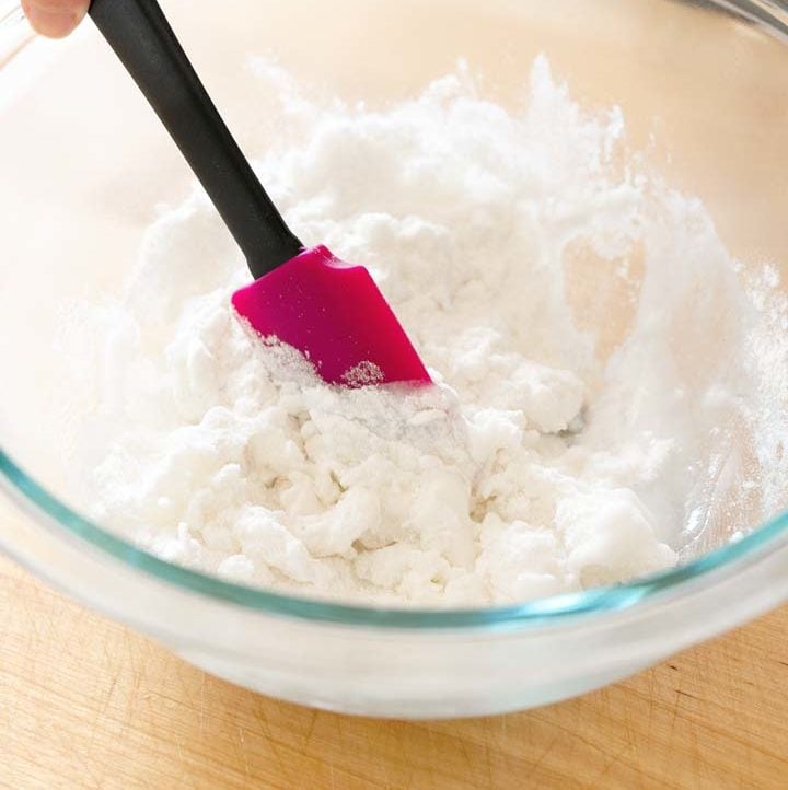 mixing of sweet rice flour dough in a glass mixing bowl with a small pink rubber spatula