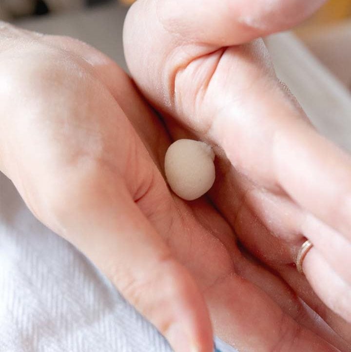 a sweet rice ball being rolled in between the palm of two hands