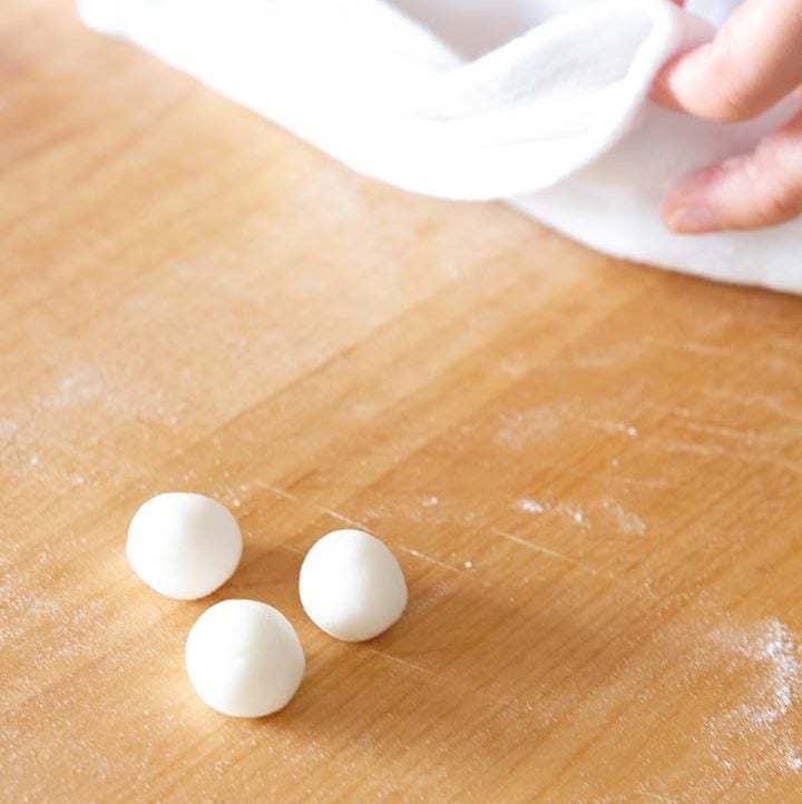 3 small white sweet rice balls on a wood cutting board