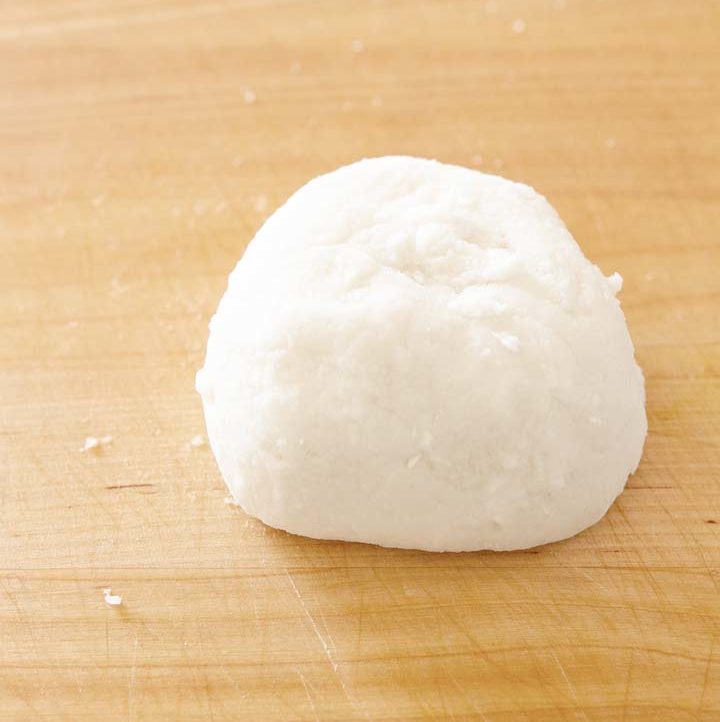 a ball of white sweet rice dough on a wood cutting board