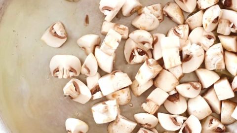 Diced button mushrooms in a pan.