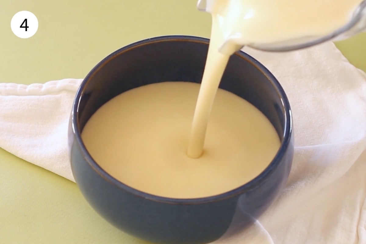 Corn potage soup being poured into a blue bowl from the blender, showing the smooth texture.