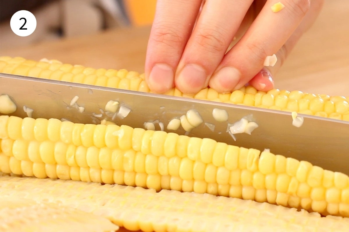 Cutting corn kernels off of an ear of boiled/steamed corn.