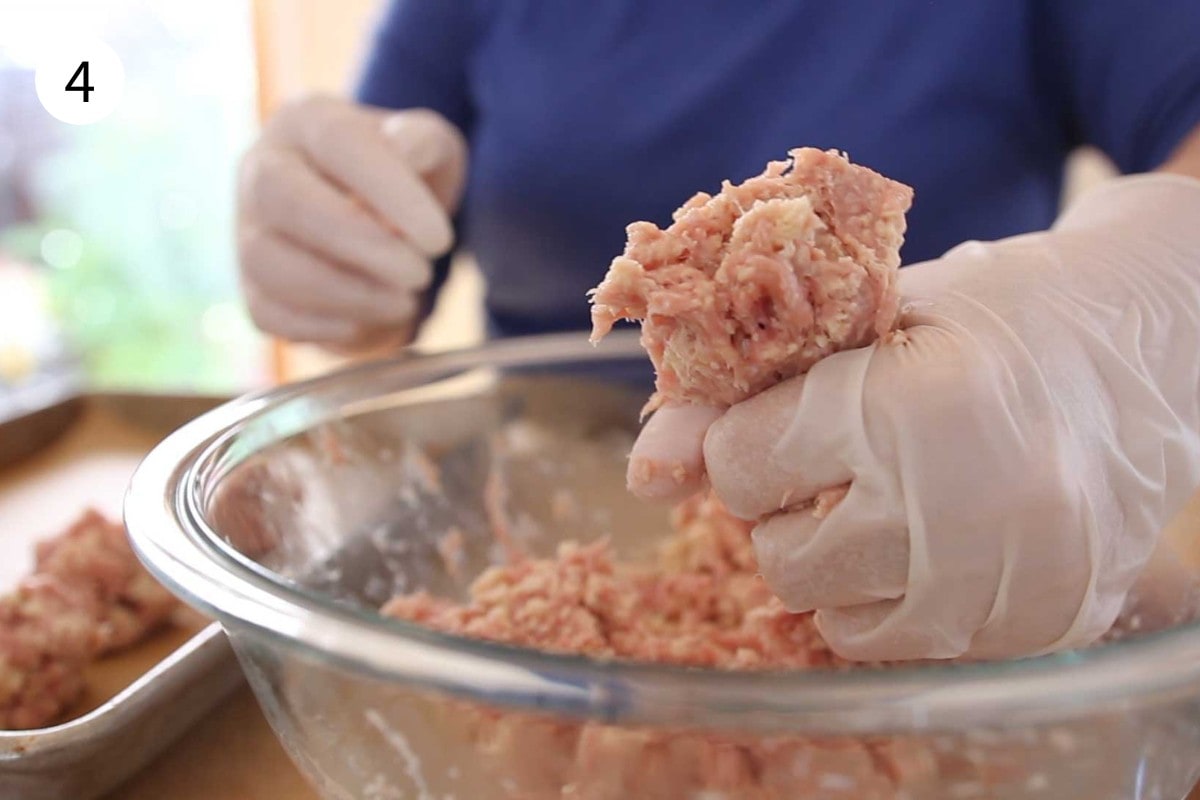 Step 2 of a chinese meatball shortcut – squeezing the meatball mixture between the thumb and index finger to form a rough ball shape.