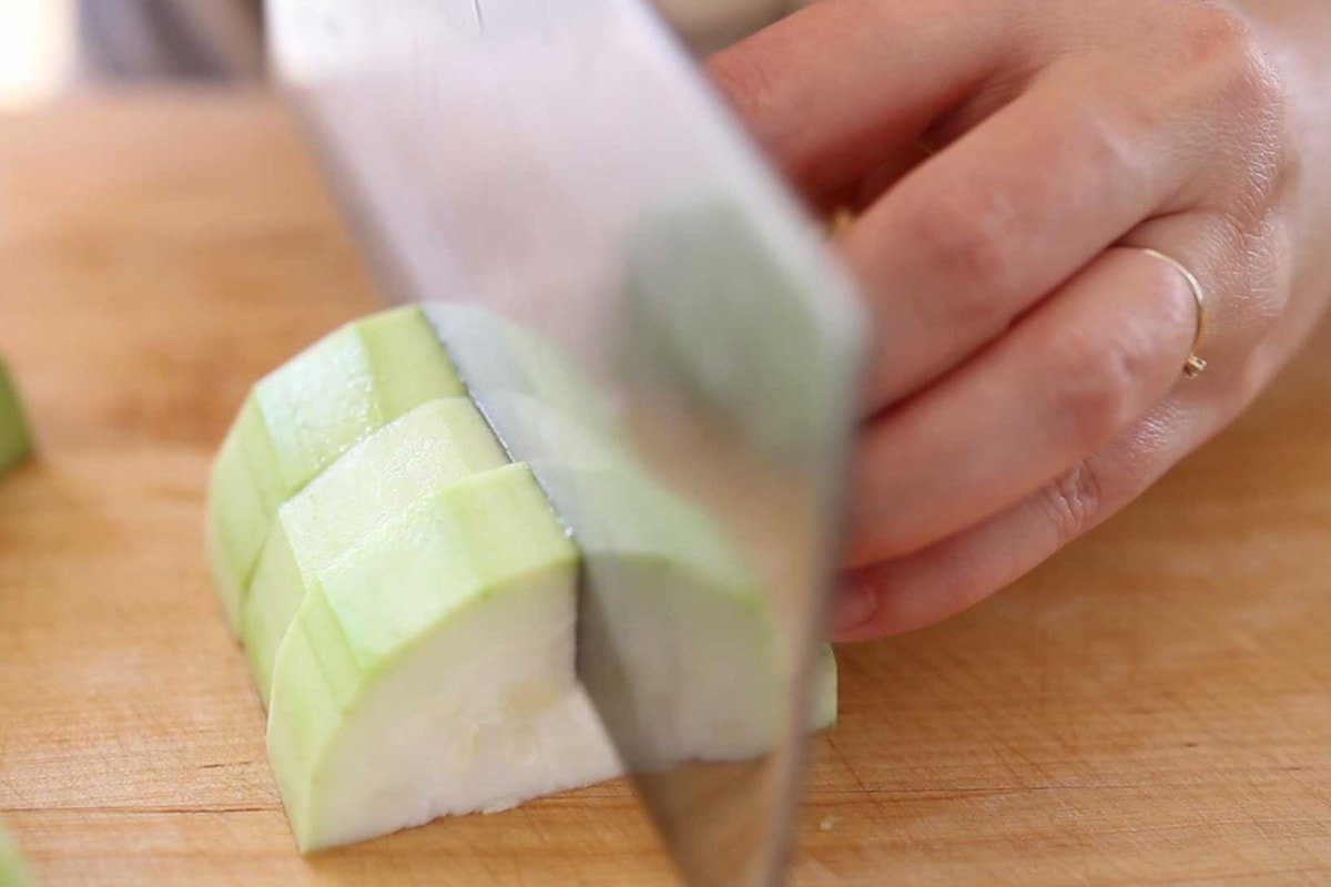 Cutting opo squash half-moon slices in half.