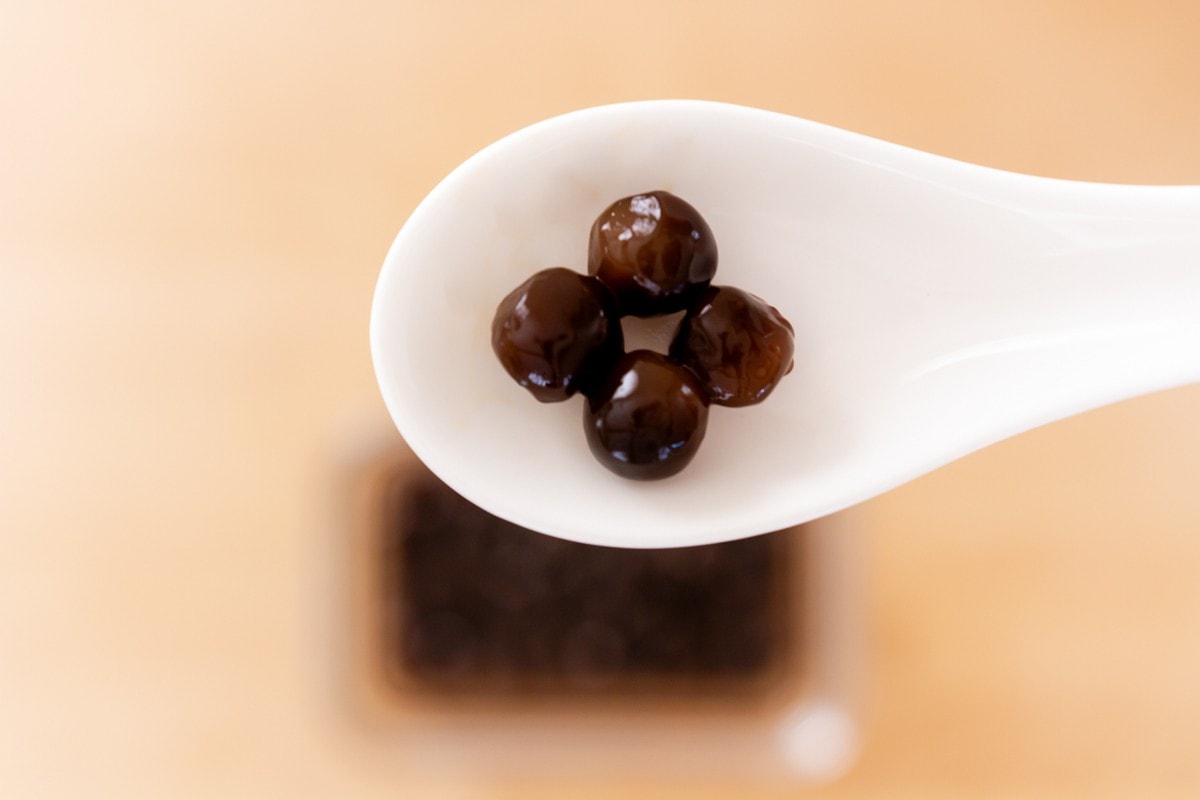 Four cooked boba (tapioca pearls) in a white soup spoon.