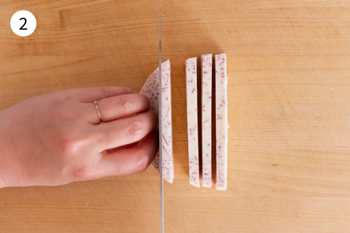 Top-down view of taro slices being cut into ¼-inch thick strips.