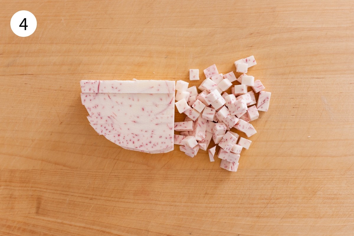 Top-down view of taro strips being cut into ¼-inch cubes.