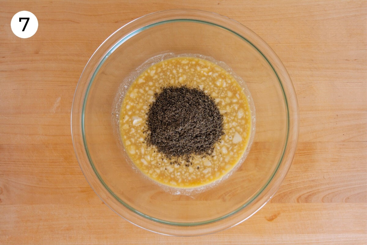Black sesame powder added to the top of the wet batter in a large mixing bowl, labeled with a circled number "7."