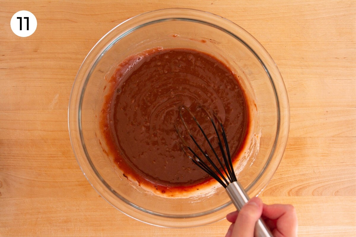 Smooth chocolate batter that's been fully mixed in a large glass bowl (though still showing some coconut milk chunks), with a circled number "11."