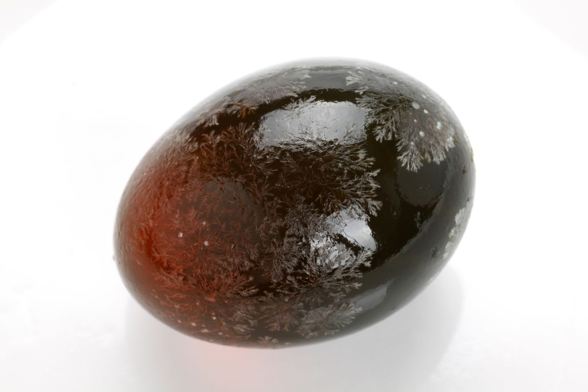 A century egg on a white surface with crystallization patterns on its surface.