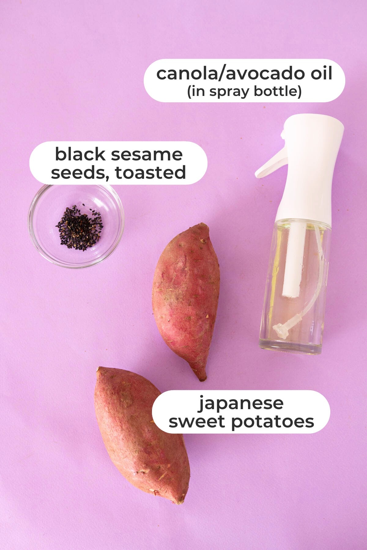 Labeled ingredients for air fryer roasted Japanese sweet potatoes over a purple background, including canola/avocado oil (in a spray bottle), toasted black sesame seeds, and Japanese sweet potatoes.