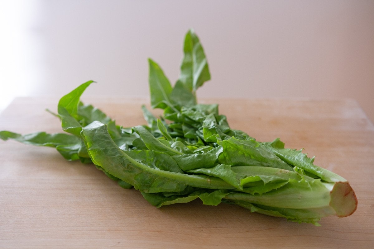 A sword leaf vegetable on a wood cutting board.