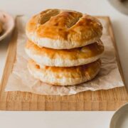 Three Chinese wife cakes stacked on a parchment covered bamboo cutting board.