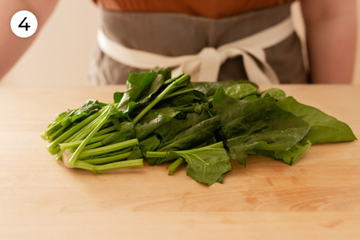 A bunch of Taiwan spinach cut into two inches long pieces on a wood cutting board, labeled with a circled number "4."
