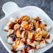 Rice noodle rolls with sauce on a white plate.