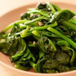 Stir-fried spinach with garlic in a pink serving plate.