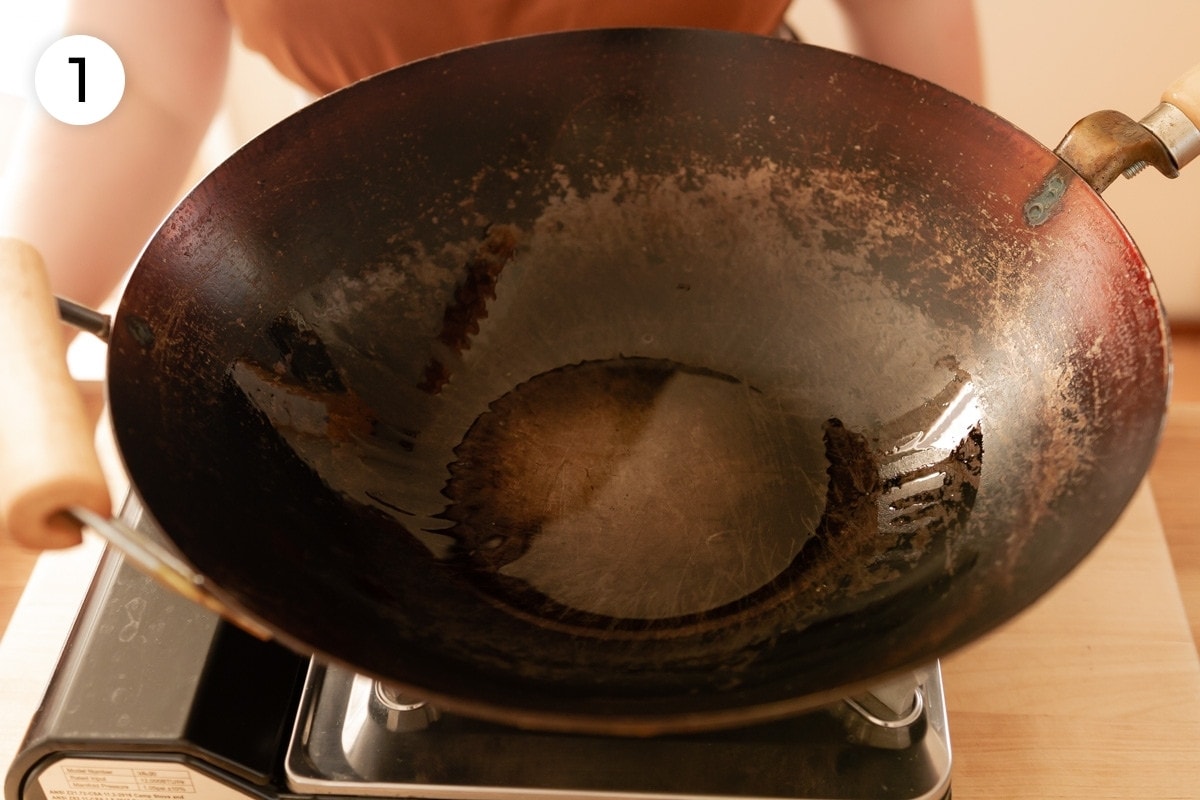 Top down view of a heated wok with canola oil in it, labeled with a circled number "1."