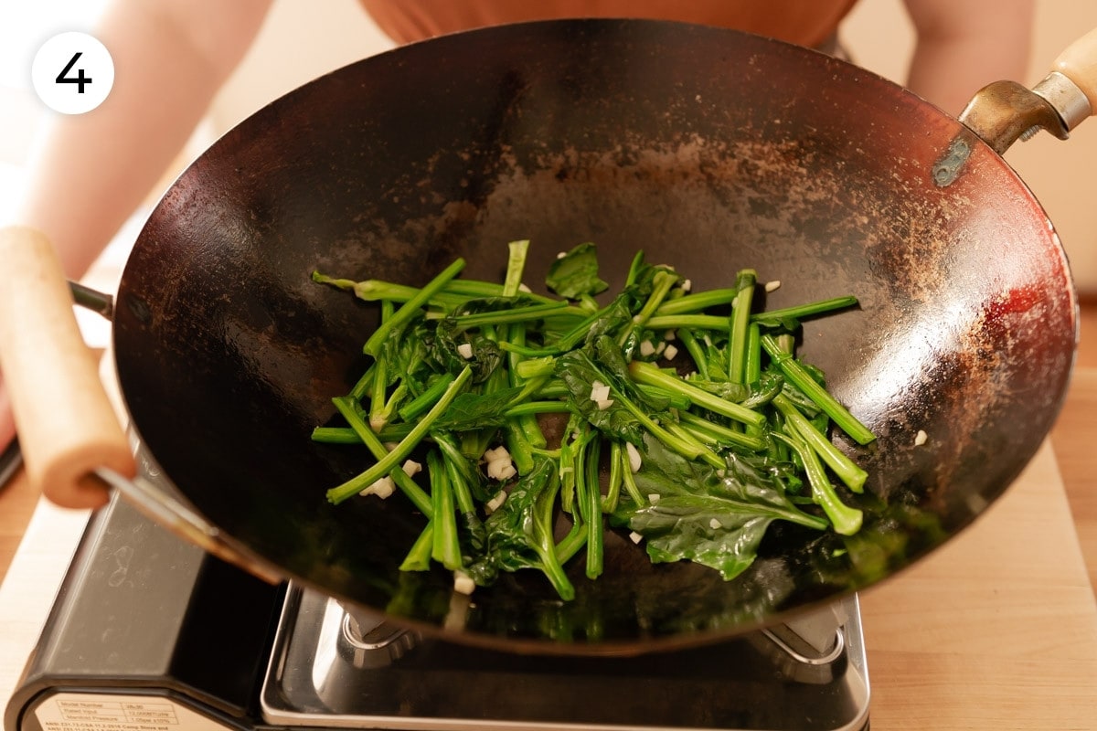 Top down view of just wilted spinach stems in a heated wok, labeled with a circled number "4."