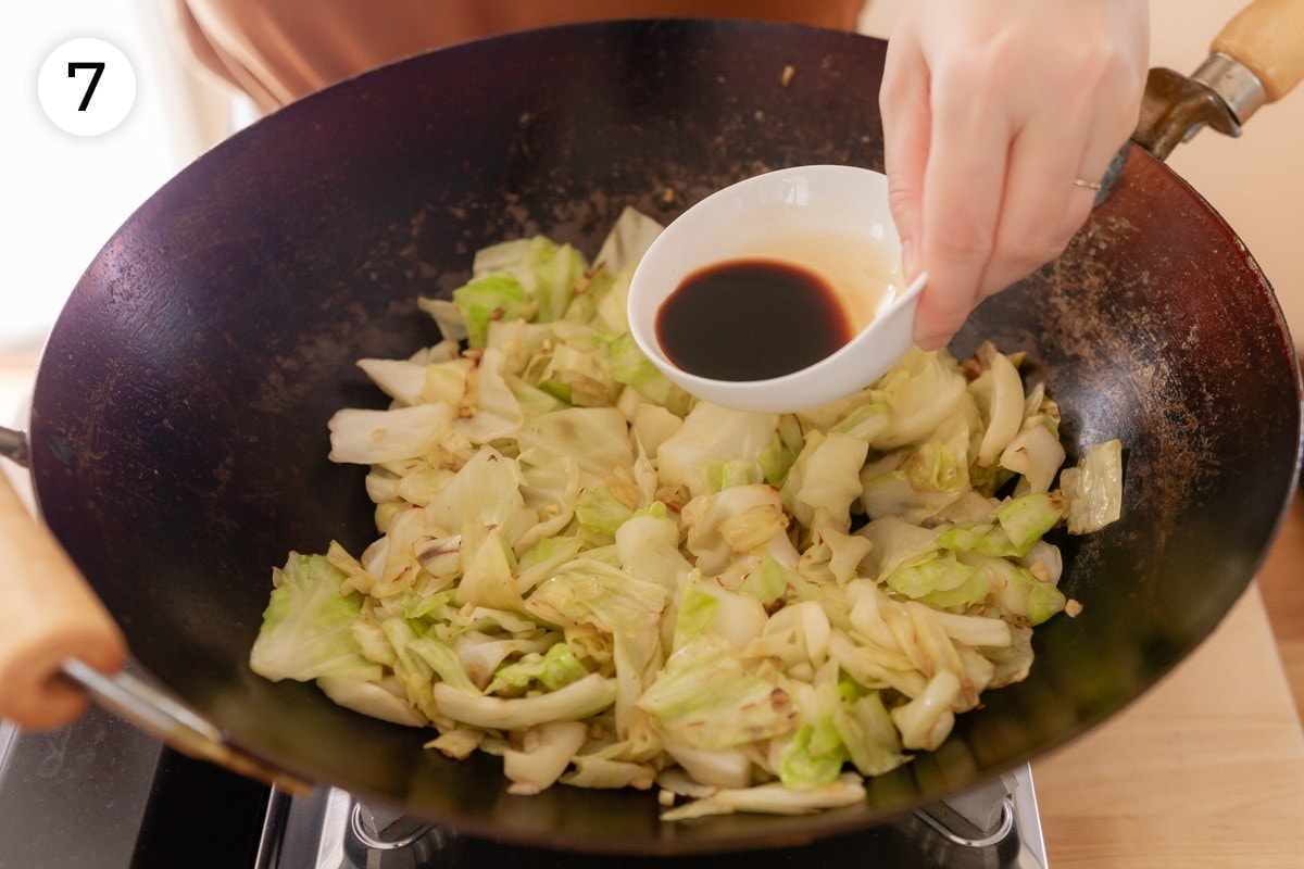 Cindy pouring low sodium soy sauce over the more charred cabbage in the wok, labeled with a circled number "7."