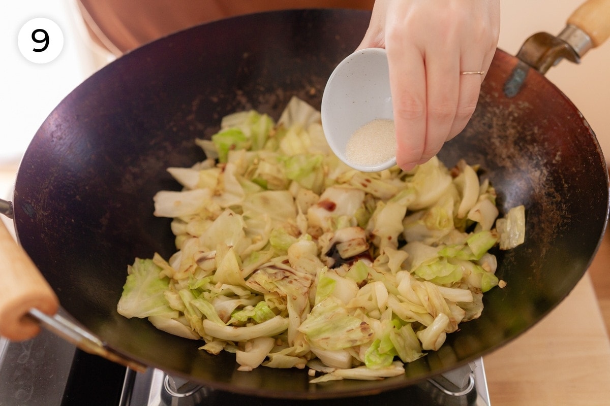Cindy pouring sugar over the cabbage in the wok, labeled with a circled number "9."