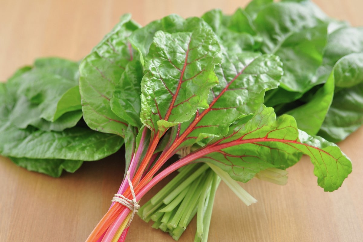 Two small bunches of swiss chard on a wood surface.