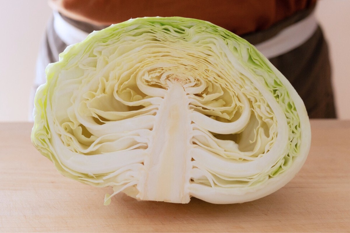A Taiwanese cabbage cut in half on a wood cutting board with the cut side showing.