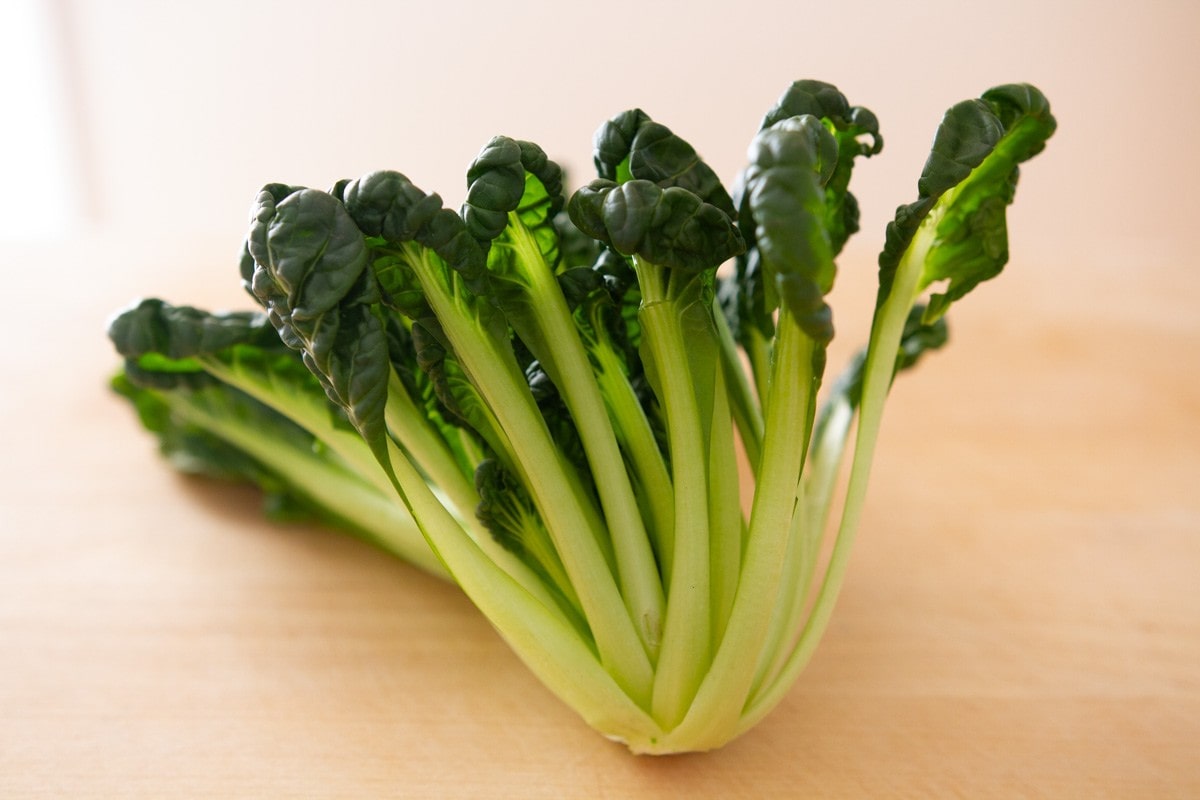 A head of tatsoi on a wood cutting board.