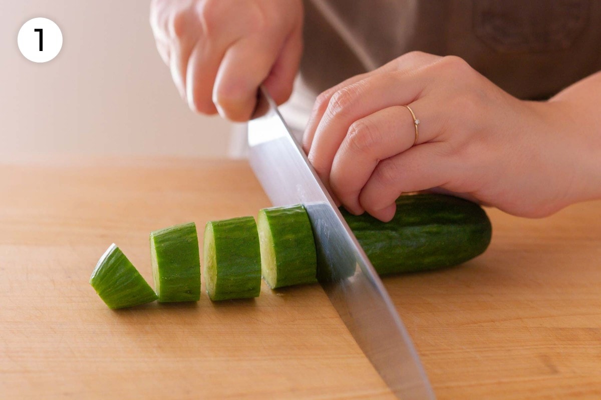Recipe step 1: Cindy cutting a Persian cucumber into ¾-inch (19 millimeters) thick slices with a chefs knife.