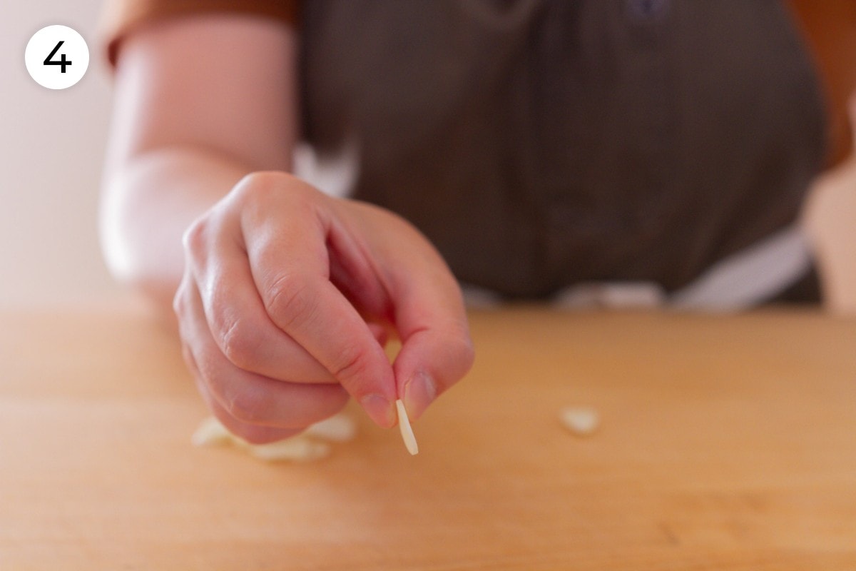 Recipe step 4: Cindy holding up a thin slice of garlic, showing that it's about ¼-inch (6.5 millimeters) thick.
