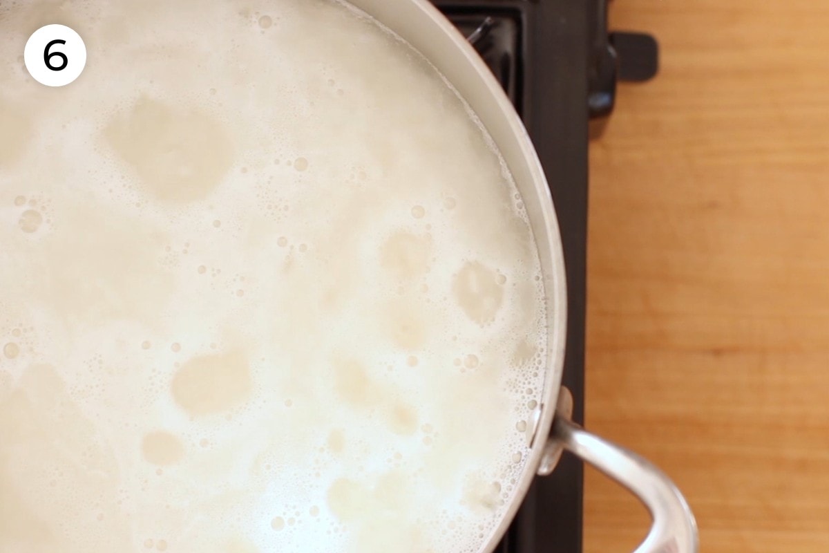 Recipe step 6: Top-down view of congee simmering in a medium pot.
