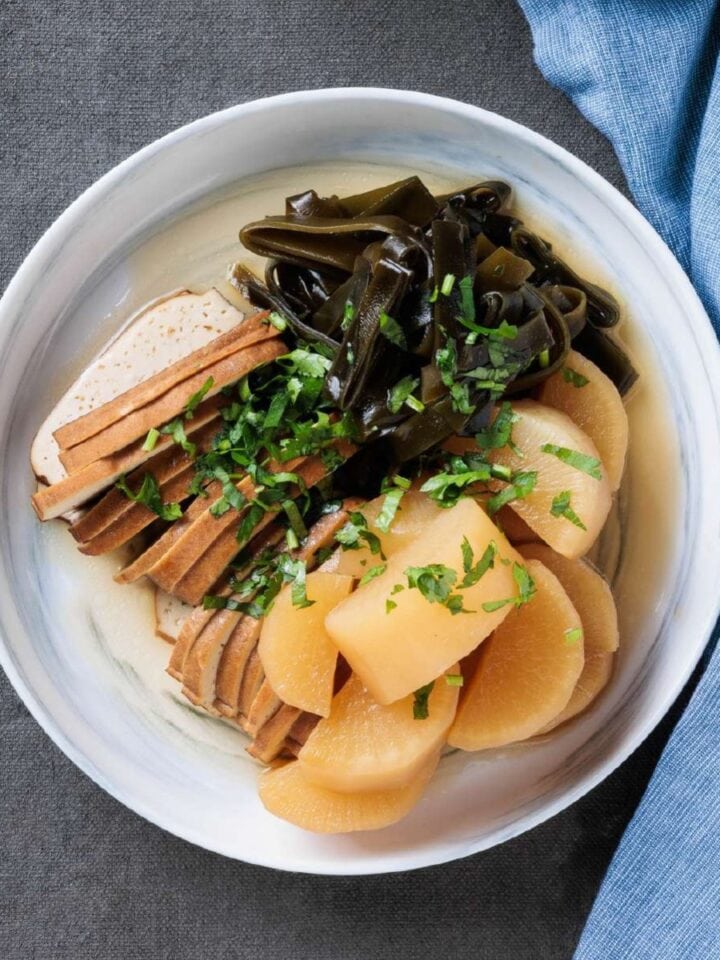 Taiwanese-style braised tofu, white radish, and konbu (kelp) served on a white dish and topped with the braising liquid and fresh cilantro.