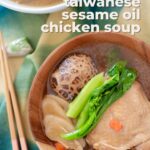 Sesame oil chicken soup in a wood bowl and a pair of chopsticks with text, "nourishing taiwanese sesame oil chicken soup" and "the sound of cooking dot com."