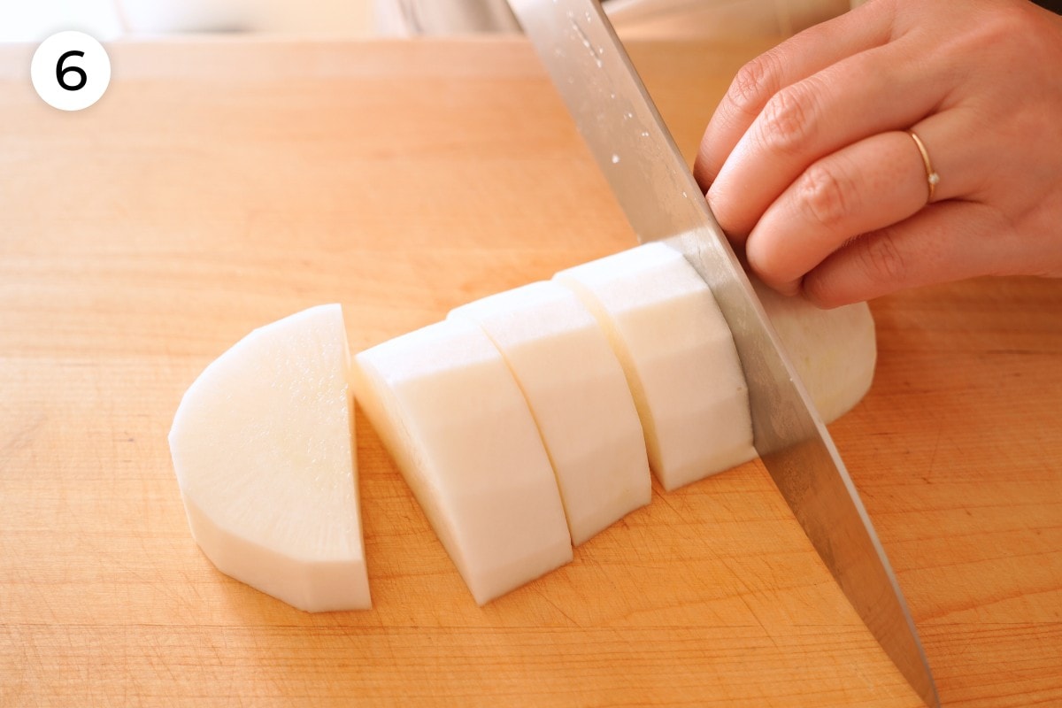 Recipe step 6: Cindy cutting one half of the daikon radish into 1 ½-inch thick half moon pieces.