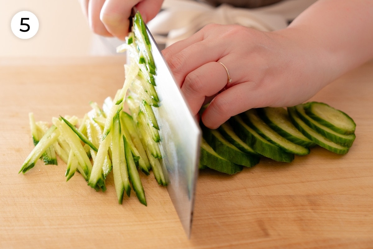 Recipe step 5: Cindy cutting the fanned out slices of cucumber into thin strips from right to left.