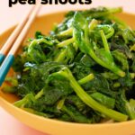 Close-up of a bowl of stir-fried pea shoots, showcasing its vibrant green color. The overlay text reads, "easy stir-fried pea shoots" and "thesoundofcooking.com" along with a logo.