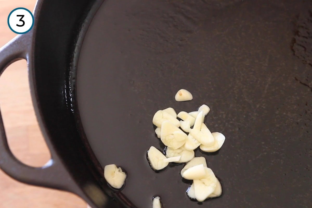 Stir-fried morning glory step 3 - Sizzling slices of garlic in a thin layer of hot oil in a cast iron pan.